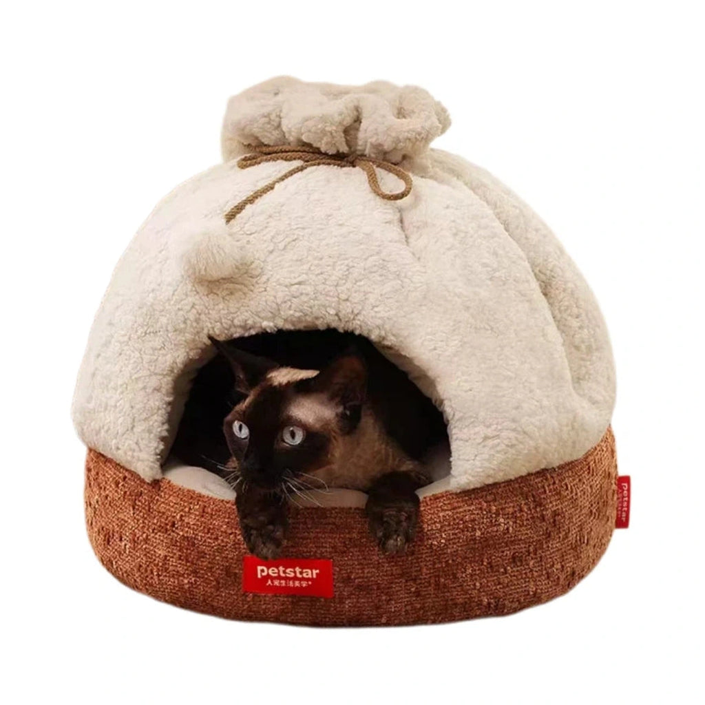 Cat in a beige Petstar plush cave bed with a brown base and pom-pom trim