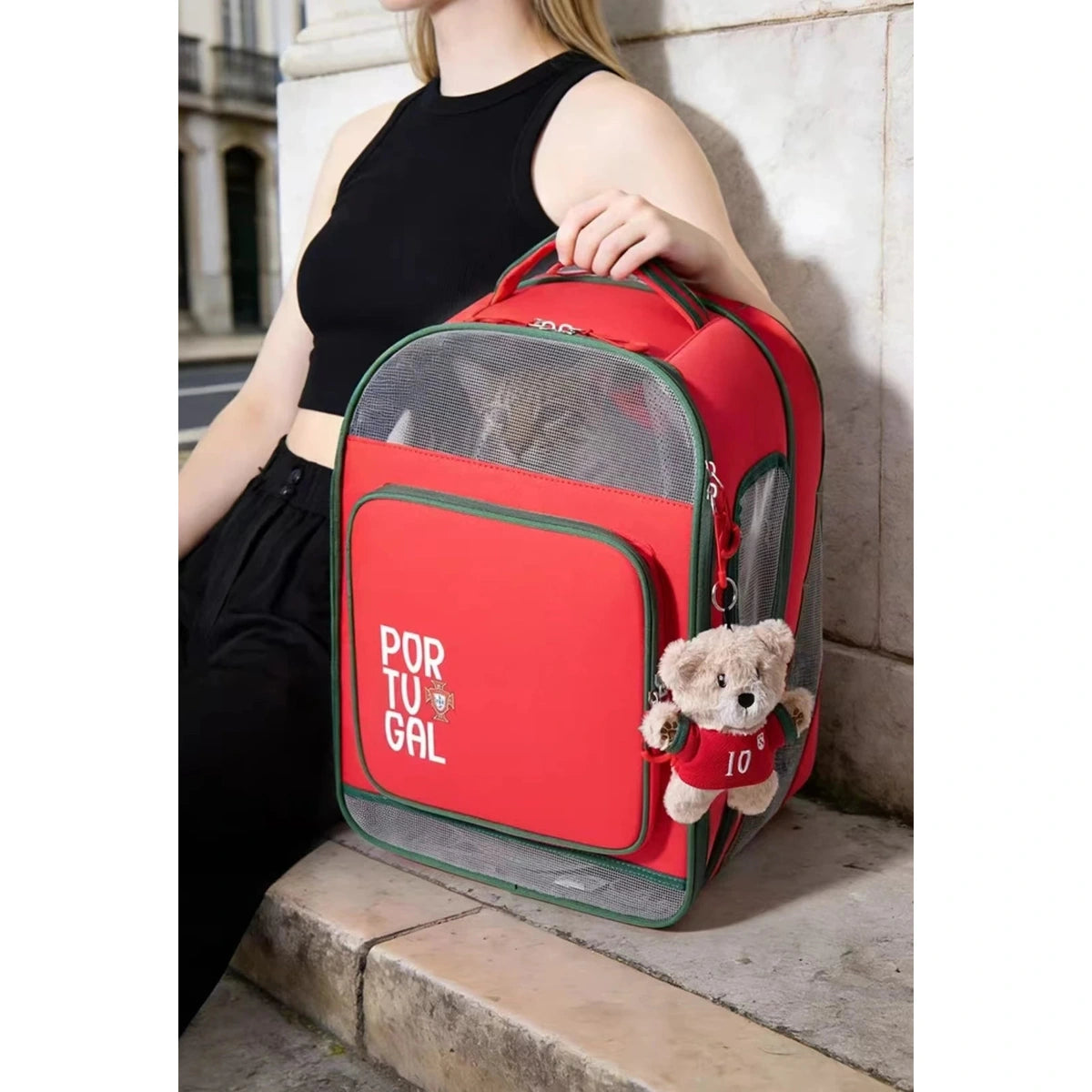 Petstar Portugal backpack held by its top handle beside a decorative bear